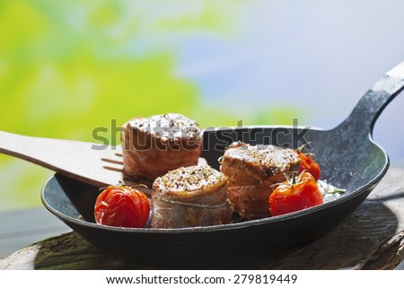 Bacon wrapped pork fillet with tomatoes in pan