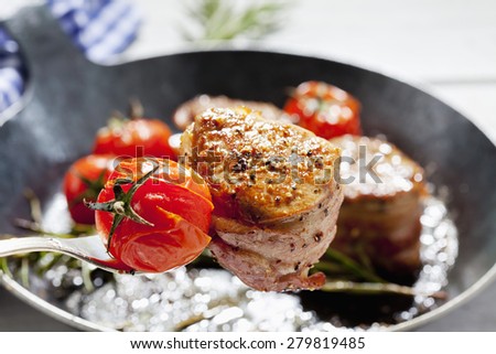 Bacon wrapped pork fillet with tomatoes in pan