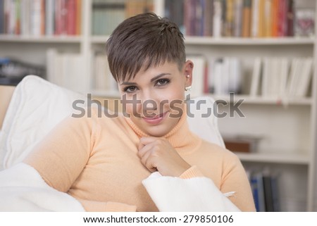 Young brunette woman sitting in front of bookshelf