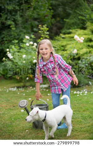 Girl trying to lift heavy watering can in garden