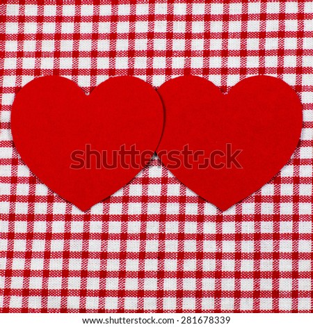 Two red hearts on red white checked cloth