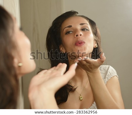 Young woman blowing kiss at her mirror image