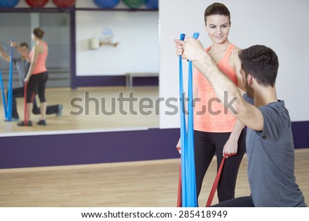 Couple training in fitness studio with resistance band