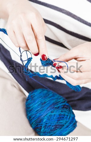 Woman knitting blue scarf with blue wool
