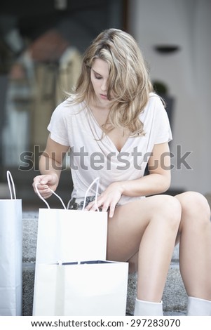 Germany,Lower Bavaria,Landshut,View of young woman looking inside shopping bags in city