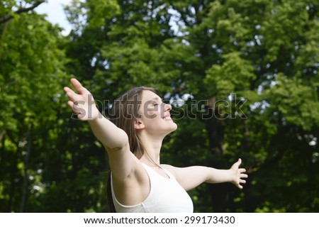 Young woman in park, arms reached out