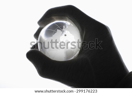 Human hand with cotton gloves gripping glass globe against white background,close up