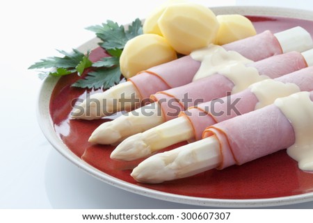 Asparagus,potatoes,ham and parsley in plate on white background