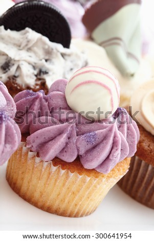 Close up of buttercream black currant cupcake with chocolate truffle against white background