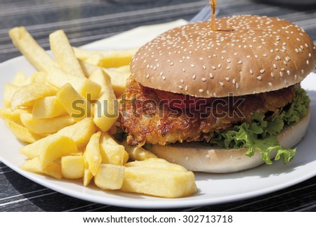 Close up of burger made of fried turkey with french-fried potatoes