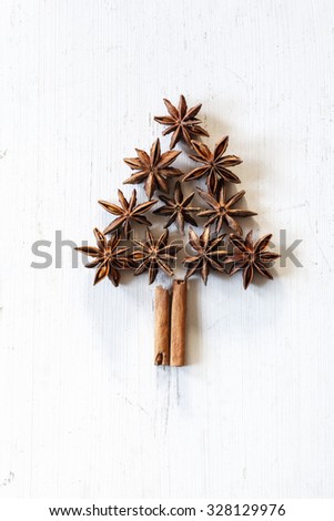Christmas tree of cinnamon sticks and star anise on white wood