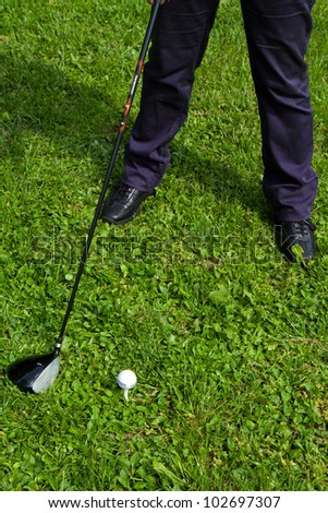 Golf ball on tee in front of driver