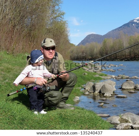 father and daughter fishing on river on summer day