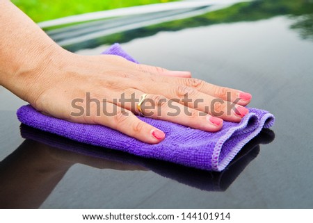 A Hand drying a back car with a synthetic  cloth