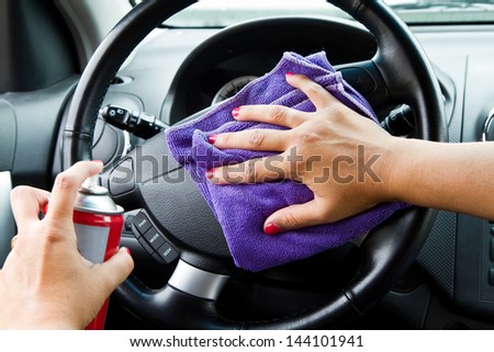 Woman\'s hand with microfiber cloth polishing wheel of a car