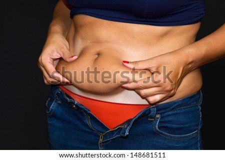 Woman\'s fingers measuring her belly fat