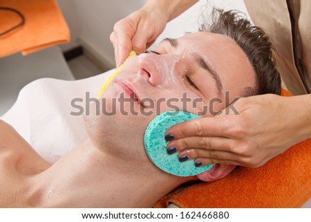 Female hands cleaning man\'s face  in a spa center