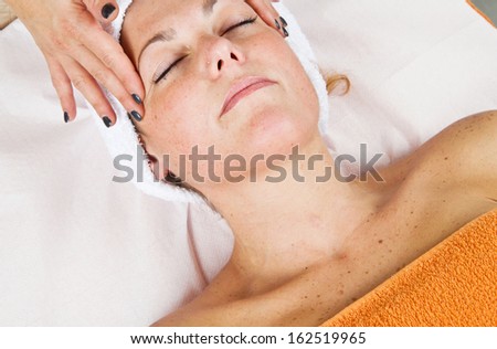 Beautiful young woman receiving facial massage with closed eyes in a beauty center