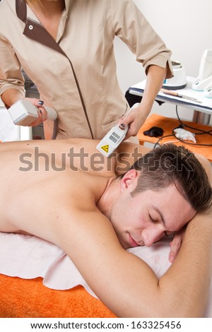 young man receiving laser epilation on beauty center