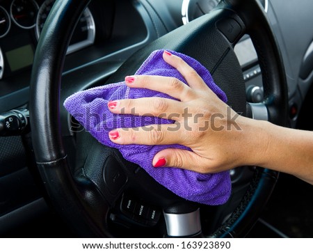 Woman\'s hand with microfiber cloth polishing wheel of a car