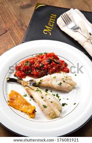 delicious monkfish with tomatoes sauce, olive and capers with menu card