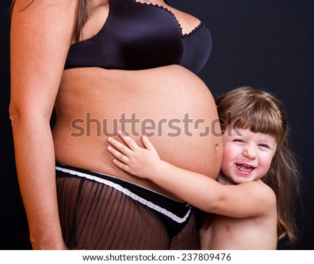 happy kid girl hugging pregnant mother\'s belly