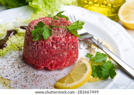Close up of beef tartar with fresh salad and lemon slice