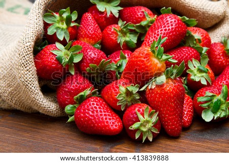 fresh strawberry in burlap sack on wood