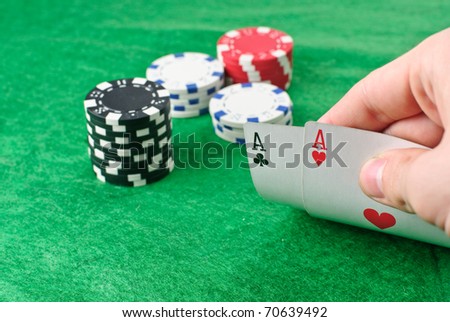 Poker chips and a hand flip the cards isolated against green felt