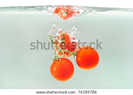 tomatoes splashing into water with a grey background