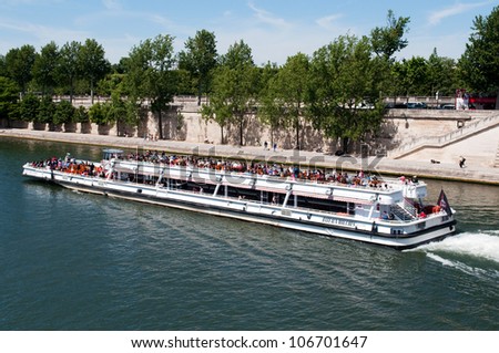 PARIS, FRANCE - MAY 28, 2011: Seine river with tourists ship in Paris on May 28, 2011, France. The Seine is a 776 km long river and an important commercial and tourist waterway within the Paris area