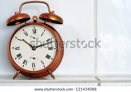 old-fashioned copper alarm clock on the mantelshelf