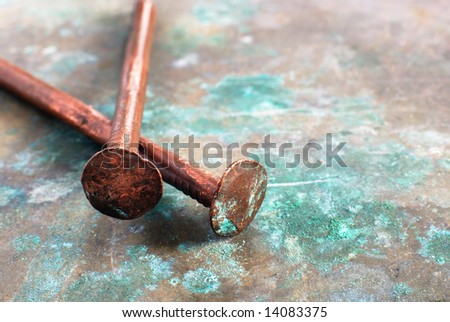 two copper nails on the metal sheet with patina