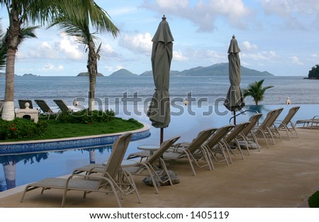 Some chairs on a beach front pool waiting for you to sit on them