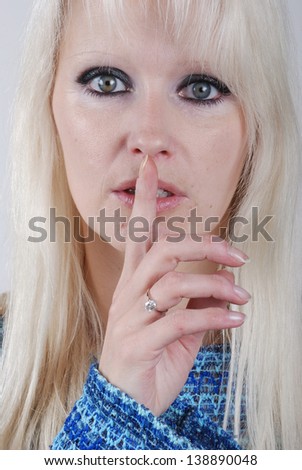 Young blond woman making silence finger over her mouth
