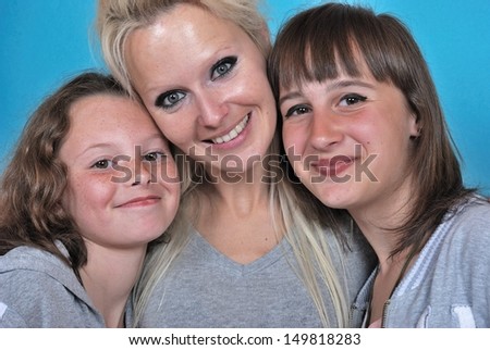 A mother smiles as she receives a kiss on the cheek from her young daughters