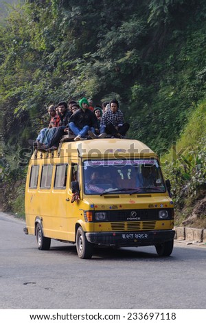 CHITWAN, NEPAL - OCTOBER 26, 2013: Local bus transportation, it is normal to see people sitting on the roof of bus. These are arguably the cheapest mode of transportation in Nepal but are too crowded.