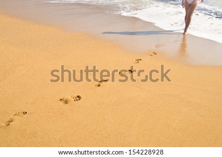 Woman\'s footprints on sand near the sea