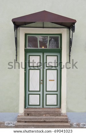Green door with roof over stairs