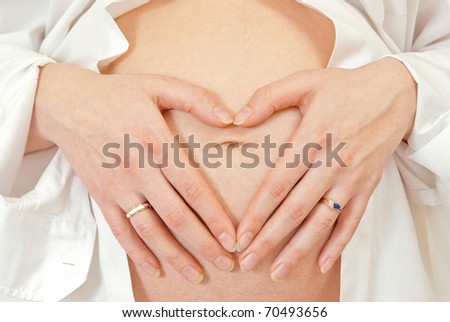 Pregnant woman holding hand on belly in shape of heart