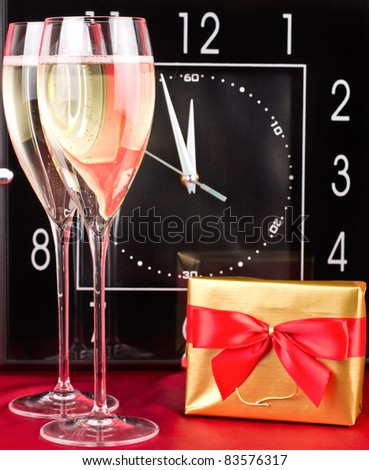 Glasses with sparkling wine and gift in front of clock. See more my Christmas related photos: http://www.shutterstock.com/sets/49317-christmas-and-new-year-2012.html?rid=522649
