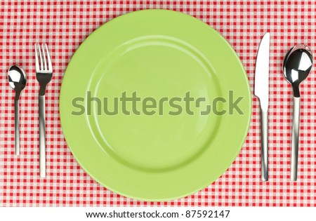 Green plate with cutlery over red tablecloth. See more my cutlery photos: http://www.shutterstock.com/sets/65705-cutlery.html?rid=522649