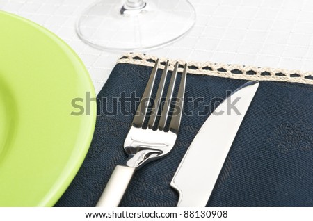 Fork and knife on napkin near green plate. See more my cutlery photos: http://www.shutterstock.com/sets/65705-cutlery.html?rid=522649