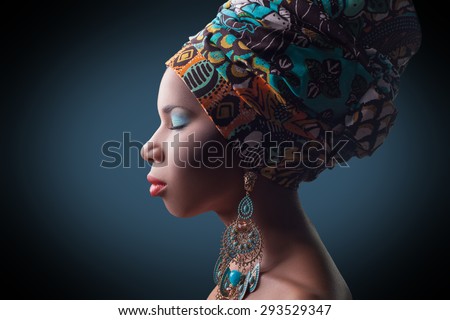 young beautiful fashion model with traditional african style with scarf, earrings and makeup on dark blue background.  \
Developed from RAW, edited with special care and attention.