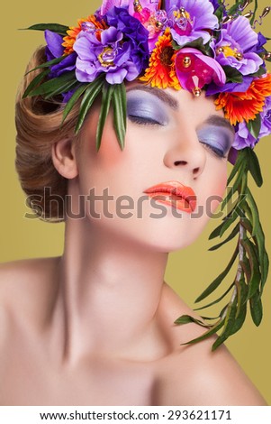 Beautiful young girl with a floral ornament in her hair, bouquet on head, looking at camera with blue eyes on yellow background.\
Developed from RAW, edited with special care and attention