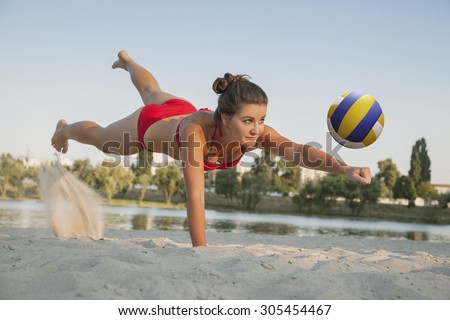 one young beautiful lady is playing volleyball on the beach, professional fly, summer time on beach. sport activity with red bikini making a save.