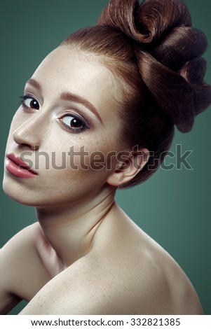 Beauty portrait of young women with red hair, dark brown eyes and a lot of freckles and hairstyle and white skin on green background looking at camera, studio shot.