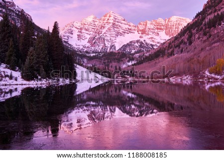 Maroon Bells and Maroon Lake with reflection of rocks and mountains in snow at sunrise around at autumn in Colorado Rocky Mountains, USA.