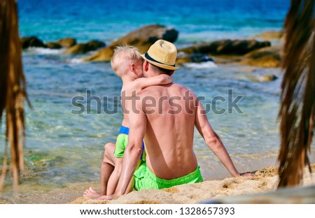 Two year old toddler boy on beach with father. Summer family vacation. Sithonia, Greece.