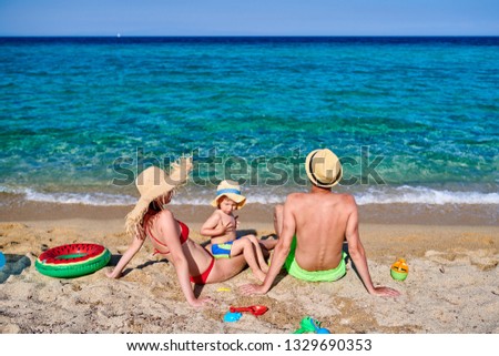 Family on beach with inflatable ring and toys. Young couple with three year old boy. Summer family vacation. Sithonia, Greece.